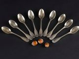 six silver spoons with nuts on a black background