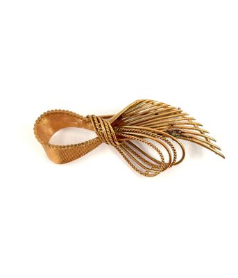 a close up of a gold bow with feathers on a white background