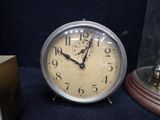 a clock that is under a glass dome on the table
