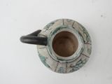 a small vase with a handle on a white surface