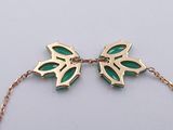 bracelet with green leaves on a gold chain on a white background