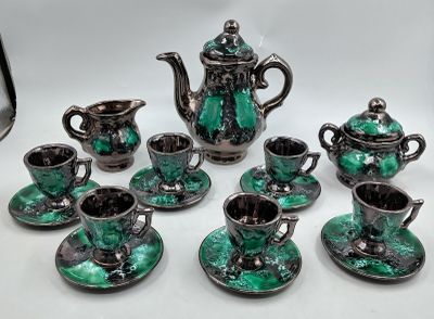 several pieces of green and black tea set on a white table
