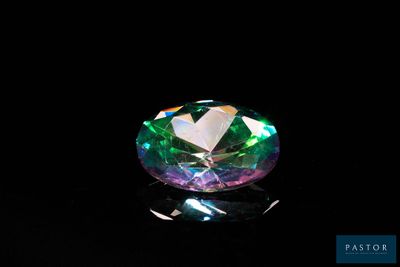 a close up of a green and purple diamond on a black surface