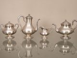 trois théières en argent posées sur une table en verre