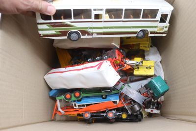 une personne tenant un bus miniature dans une boîte remplie de jouets