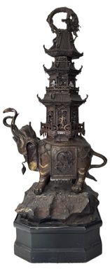 statue en bronze représentant un éléphant et une pagode posés sur un rocher