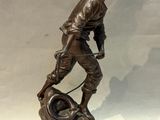 bronze statue of a man with a wheel on a white background