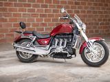a red motorcycle parked in front of a brick wall