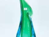 the green and blue glass vase is sitting on a white surface