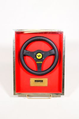un volant dans une boîte rouge ornée d'une plaque dorée