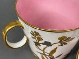 a pink cup and saucer sitting on a table