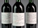 three bottles of red wine are lined up on a table