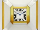 une image représentant une horloge carrée dorée et blanche avec des chiffres romains