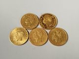 five gold sovereigns, one of which has a crown on top of it