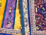 two pieces of cloth with colorful designs on them on a white surface