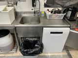 a kitchen with a sink and a trash can in it