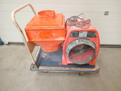 une soufflerie orange posée sur un chariot dans un garage