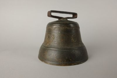 an old bell with a wooden handle on a white surface