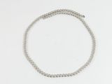 un gros plan d'un bracelet en perles argentées posé sur une surface blanche