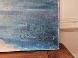une peinture représentant une scène de plage posée sur une table en bois