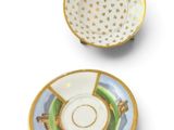 a close up of a cup and saucer on a white surface