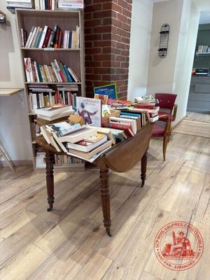 une table sur laquelle sont posés de nombreux livres, dans une pièce
