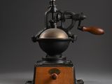 an old coffee grinder with a wooden handle on a grey background