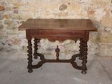a small table with a drawer on it in front of a brick wall
