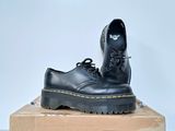 black dr martenshoes on top of a box on a white surface