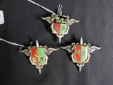 three silver and red metal ornaments on a black cloth