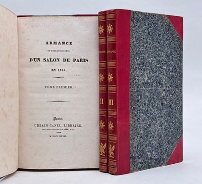 un livre ouvert posé sur une table blanche, à côté d'un livre rouge
