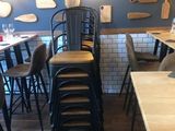 tables and chairs in a restaurant with a wall of cutting boards on the wall