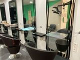 des miroirs accrochés au mur d'un salon de coiffure, avec des fauteuils et une table