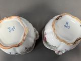 pair of porcelain bowls with floral designs on them sitting on a table