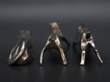 three pairs of silver shoes that are on a black surface