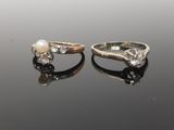 two gold rings with pearls and diamonds on a black surface
