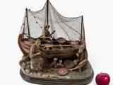 une figurine représentant un bateau avec des personnages à bord et une pomme