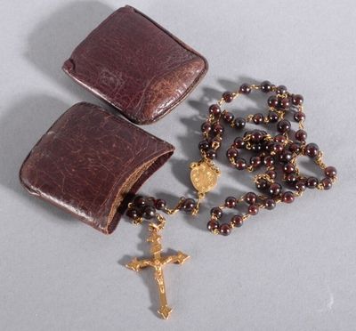 rosary and leather case with gold cross on grey background