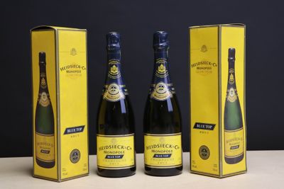 trois bouteilles de champagne posées sur une table, à côté d'une boîte