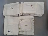 several white napkins with embroidered flowers are arranged on a table
