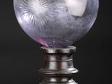 une image représentant une boule de cristal posée sur un socle en bois