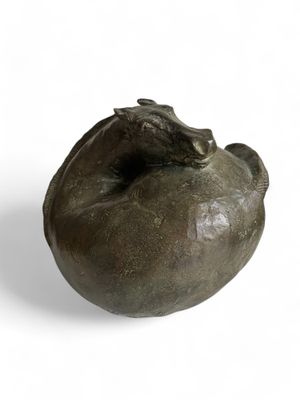 sculpture représentant une grenouille posée sur une grenade, sur fond blanc