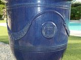 a large blue vase sitting on the grass by the pool