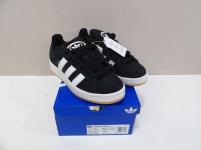 black and white adidas sneakers on a blue box on a white surface