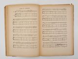 an open book with music notes on it sitting on a table