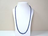 collier de perles bleues sur un mannequin à socle blanc