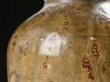 a brown vase sitting on a table with a black background