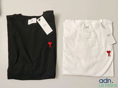 deux t-shirts blancs et noirs ornés de cœurs rouges, posés sur une table