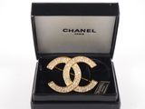a chanel brooch with gold and diamonds in a black box