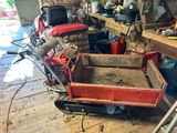 a red cart with dirt in it in a garage